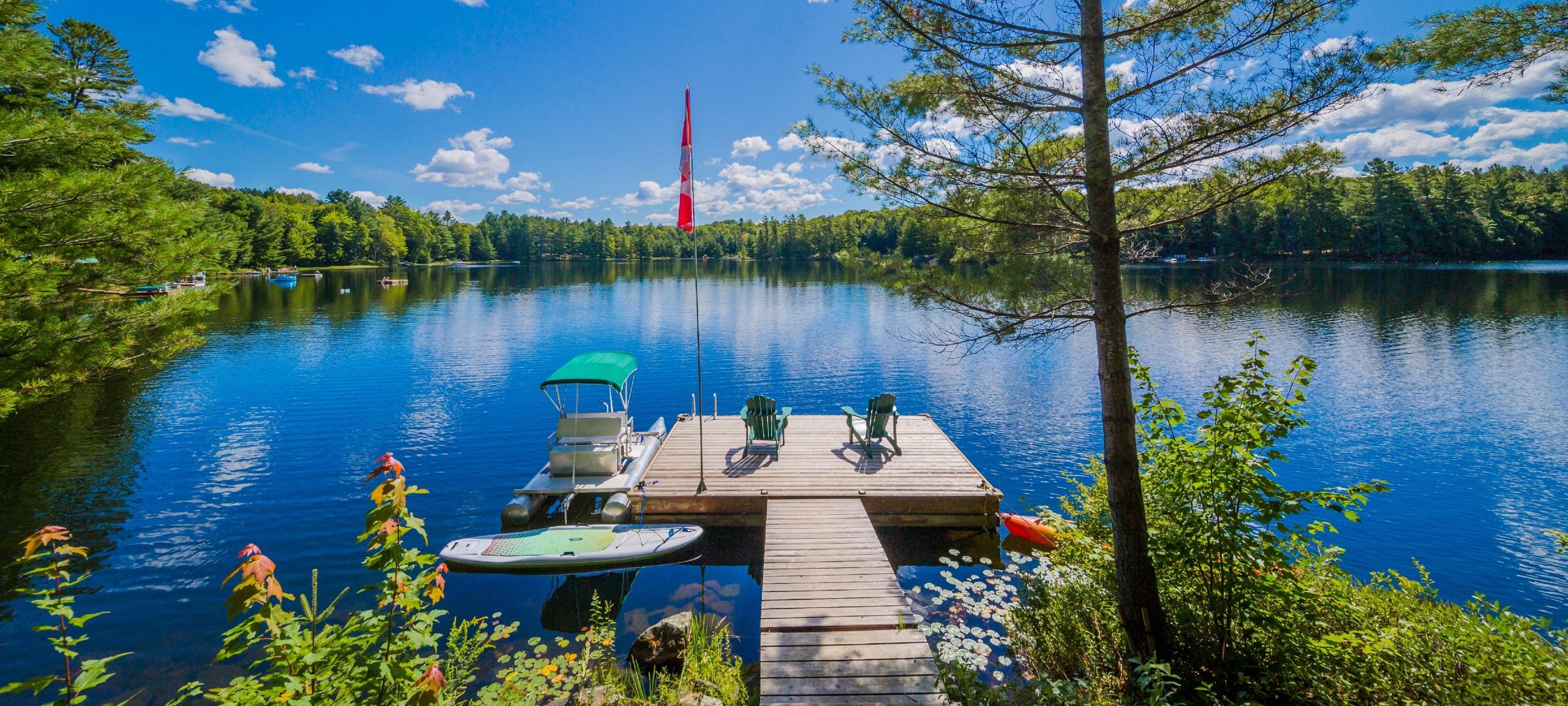 Gorgeous lake view from home dock in Muskoka, with two chairs and a boat
